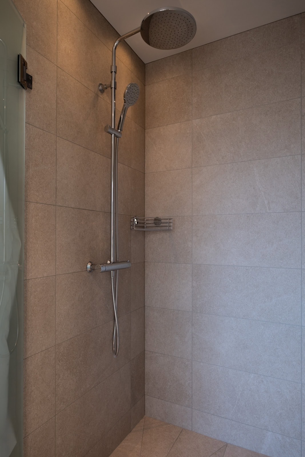 Shower cubicle with overhead shower and stone-effect tiles on the walls