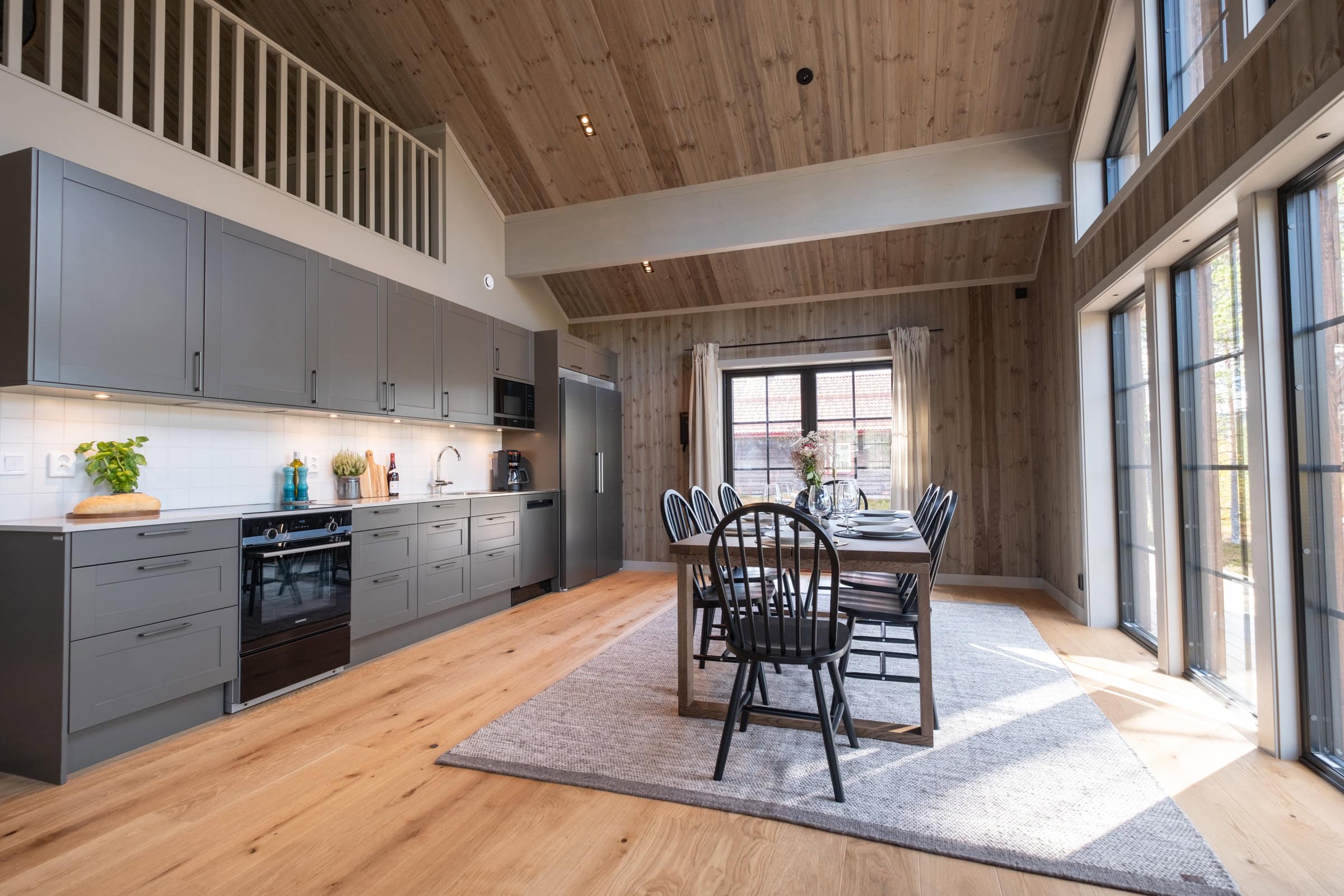 Kitchen with grey cupboard doors and a dining area; the loft is visible above